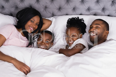 Portrait of happy family lying together on bed