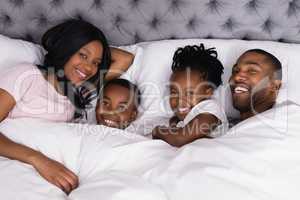 Portrait of happy family lying together on bed