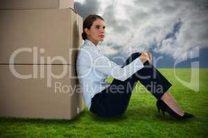 Composite image of businesswoman leaning on cardboard boxes against white background