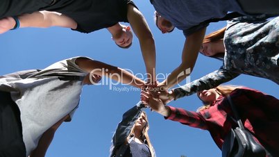 College students stacking hands on park lawn