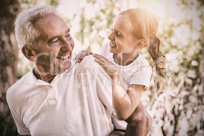 Smiling grandfather carrying granddaughter piggyback