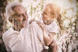 Smiling grandfather carrying granddaughter piggyback