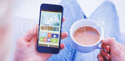 Composite image of woman using her mobile phone and holding cup of coffee