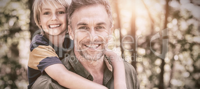 Smiling father piggybacking son in forest