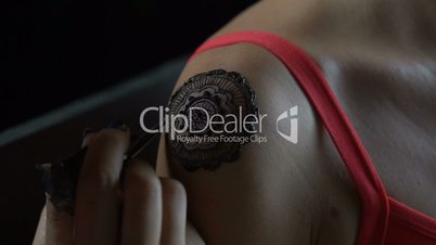 Woman gets henna tattoo on her shoulder
