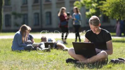 Handsome male student studying with laptop in park