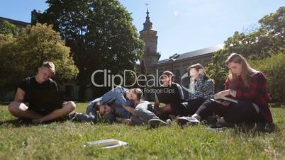 Group of tired students studying hard on park lawn