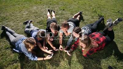 Top view teenagers in circle using phones in park