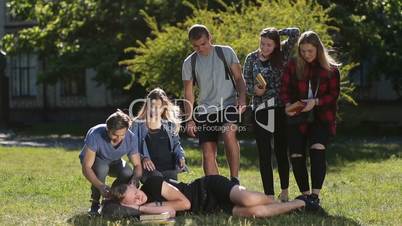 Group of students waking up sleepy friend in park