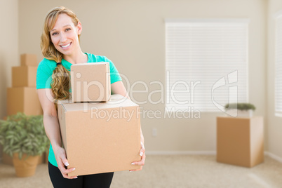 Happy Young Adult Woman Holding Moving Boxes In Empty Room In A