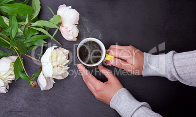Yellow mug in female hands on black background