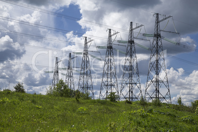 high voltage power pylons on against cloudy sky