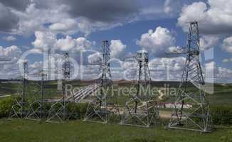 high voltage power pylons on against cloudy sky