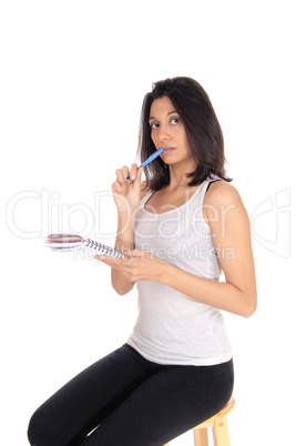 Woman talking nots with pen in mouth.