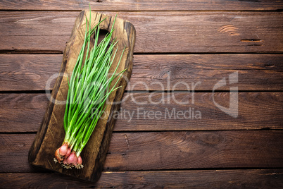 Green onion or scallion on wooden board, fresh spring chives