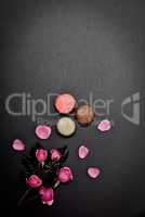 black background with macaroons and a bouquet of pink roses