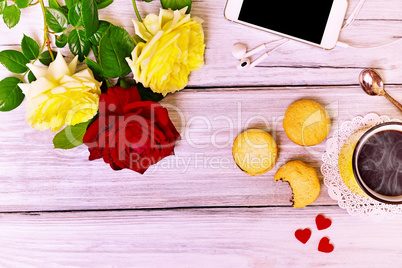 Hot coffee in a yellow mug, biscuit and mobile phone