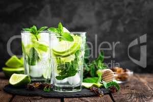 Refreshing mint cocktail mojito with rum and lime, cold drink or beverage with ice on black background