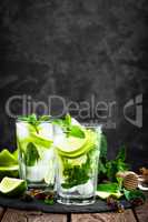 Refreshing mint cocktail mojito with rum and lime, cold drink or beverage with ice on black background