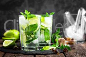 Refreshing mint cocktail mojito with rum and lime, cold drink or beverage with ice on black background