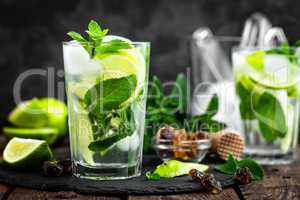 Refreshing mint cocktail mojito with rum and lime, cold drink or beverage with ice on black background