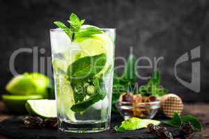 Refreshing mint cocktail mojito with rum and lime, cold drink or beverage with ice on black background