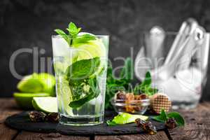 Refreshing mint cocktail mojito with rum and lime, cold drink or beverage with ice on black background