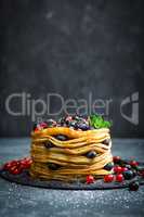 Pancakes with fresh berries and maple syrup on dark background, closeup