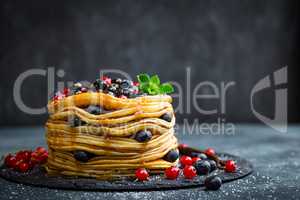 Pancakes with fresh berries and maple syrup on dark background, closeup