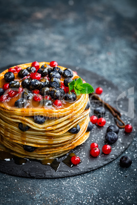 Pancakes with fresh berries and maple syrup on dark background, closeup