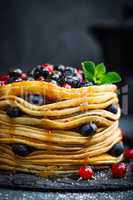 Pancakes with fresh berries and maple syrup on dark background, closeup