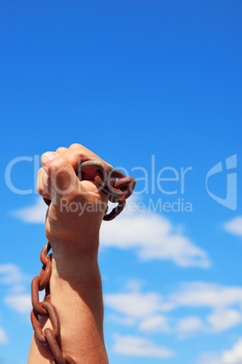male hand holds a rusty metal chain