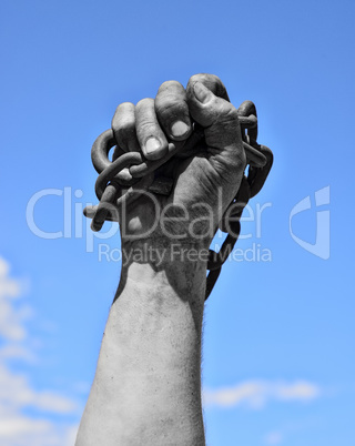 Dirty hand with chain against the blue sky