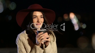 Attractive girl enjoying cup of coffee at night