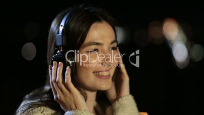 Girl listening to music with headphones at night