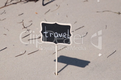 Black wooden board with inscription travel on the seashore