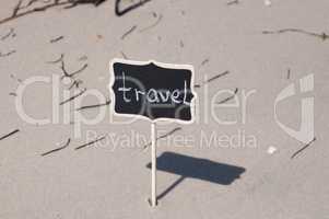 Black wooden board with inscription travel on the seashore