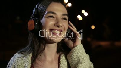 Joyful girl listening music with earphones at night