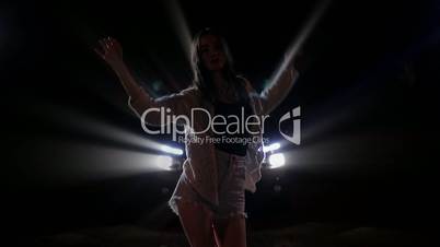 Silhouette of young woman dancing in car lights