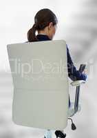Back of seated business woman with phone against blurry grey stairs