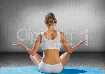 Back of woman meditating against grey wall