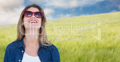 Woman in sunglasses smiling against blurry meadow on summer day