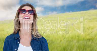 Woman in sunglasses smiling against blurry meadow on summer day