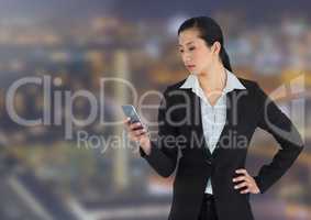 Businesswoman texting against buildings in background