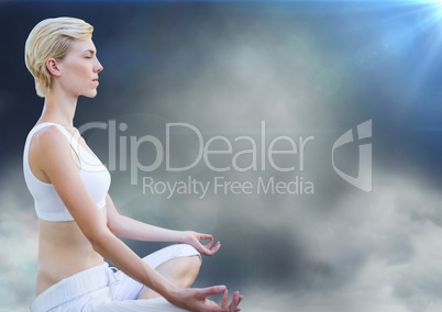 Woman meditating against clouds and flares