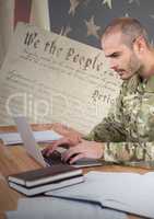 Proud soldier using a laptop with american flag background