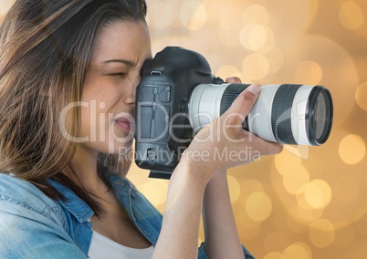 young photographer taking a photo (foreground). Gold bokeh background