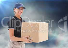 Middle aged delivery woman with box against clouds and flares