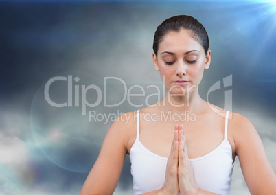 Woman meditating against cloud and flares