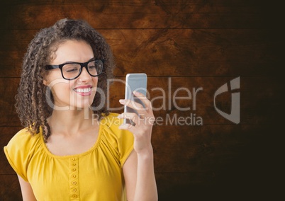 Smiling woman texting against wooden background